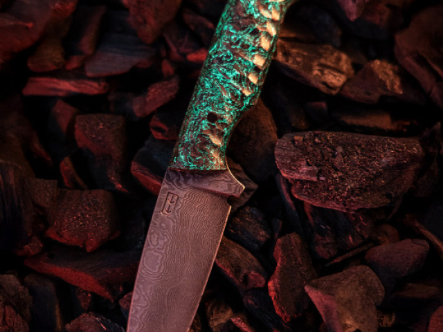 M'Nox Knife mit grünem Griff auf glühender Kohle