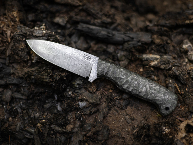 M'Nox Knife mit Damastklinge auf Waldboden