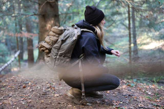 Frau mit Helikon-Tex Rucksack in der Hocke im Wald