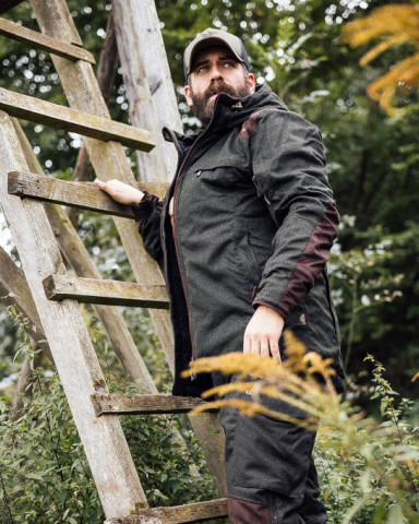Jäger mit moderner Lodenjacke am Hochsitz – robuste Bekleidung zwischen Tradition und Technik.