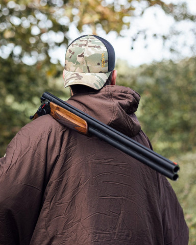 Jäger mit Tarn-Cap und Schrotflinte über der Schulter – taktische Elemente treffen klassische Jagd.