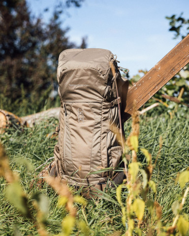 Eberlestock-Rucksack in Olivgrün lehnt an Jagdleiter – funktionales Packkonzept für modernes Weidwerk.