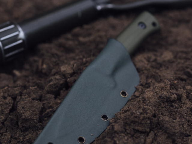 FOSSOR MK1 in passgenauer Kydexscheide auf Waldboden.